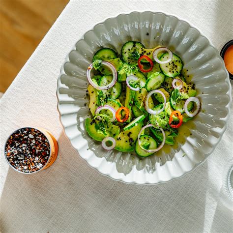 Plato de ensalada fresca de pepino y aguacate junto a una porción de camarones