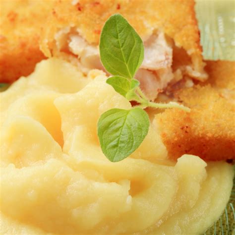 Fotografía de un plato de reineta en panko servido con puré rústico y una rodaja de limón