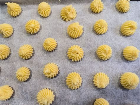 Manga pastelera formando galletas sobre papel de horno