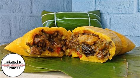 Imagen de una hallaca venezolana tradicional abierta sobre su hoja de plátano mostrando el relleno y la masa colorida.