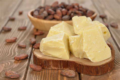 Bloque de manteca de cacao en primer plano con granos de cacao de fondo