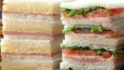 Plato con varios sándwiches de miga triangulares, algunos con pan blanco y otros con pan oscuro, mostrando diferentes rellenos.