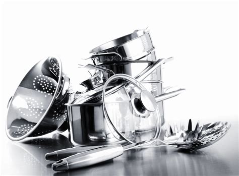 infografía: despliegue de utensilios básicos de cocina profesional dispuestos ordenadamente sobre una superficie de trabajo de acero inoxidable