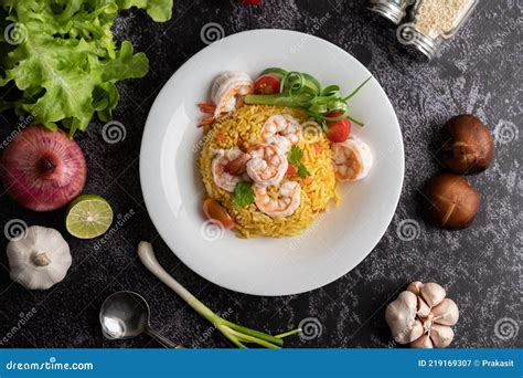 Arroz frito con camarones, tomates, zanahorias y cebolletas en un plato.