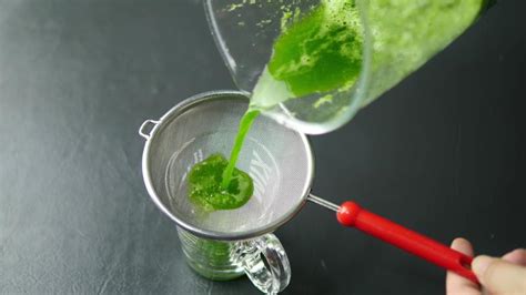 Fotografía de hojas de menta siendo maceradas en un vaso alto con un mortero.