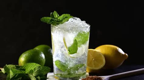 Imagen de un vaso de Mojito Azul terminado, con hielo, menta, rodajas de lima y color azul vibrante.
