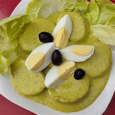 Plato de Ocopa arequipeña con papas sancochadas, huevo y aceitunas, destacando el color verde de la crema