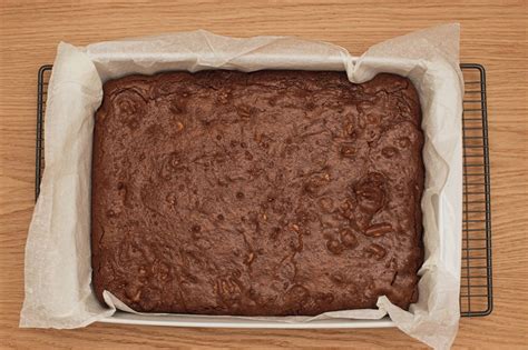 Brownie cortado en porciones sobre una rejilla, con algunas nueces encima