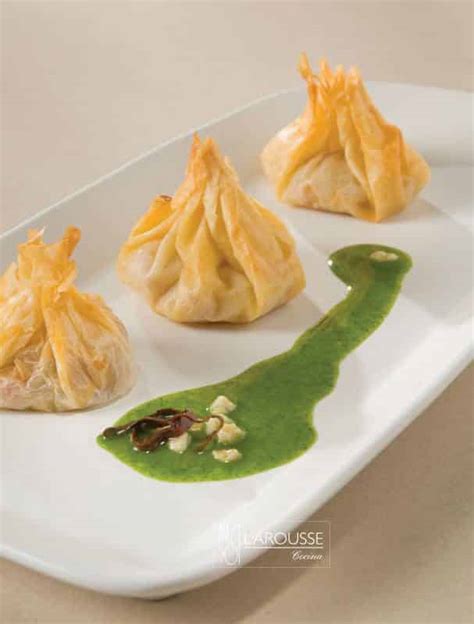 Plato de saquitos de pasta filo rellenos de marisco servidos sobre una cama de salsa cremosa