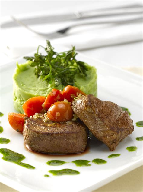 plato de filete de res con puré de arvejas y tomates cherry