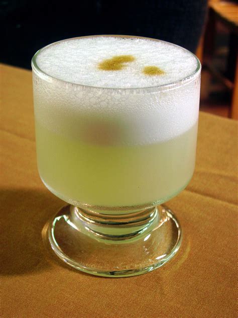Fotografía de un pisco sour servido en copa, mostrando la espuma y la decoración de Amargo de Angostura.
