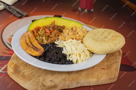 Mesa con brunch venezolano: perico, arepas, caraotas, queso, aguacate