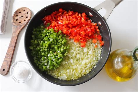 Esquema visual de los ingredientes básicos de un sofrito: cebolla, ajo, pimiento y tomate, destacando el aceite de oliva como medio de cocción.