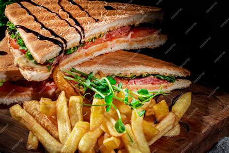 Fotografía gastronómica de un sándwich artesanal servido con guarnición de papas fritas crocantes.