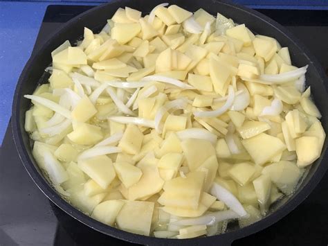 Patatas y cebolla pochadas escurriéndose en un colador