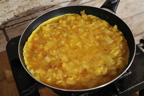 Patatas y cebolla mezclándose con huevos batidos en un bol