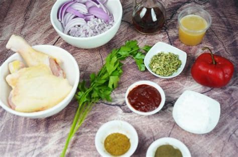 Ingredientes frescos para el adobo del pollo: hierbas, especias, aceite y vinagre
