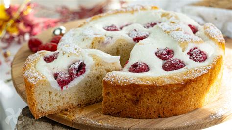 Imagen del bizcocho de ricotta y frambuesas recién horneado, con una rebanada que muestra el interior tierno y las frambuesas distribuidas.