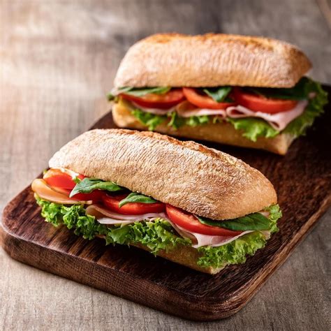 Fotografía de un combo de sandwich en ciabatta, mostrando el sandwich relleno, una lata de bebida y una pequeña porción de papas fritas.