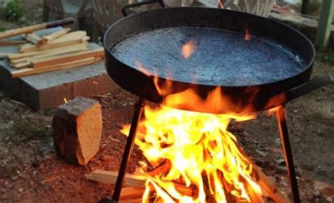 fotografía histórica: gauchos cocinando en un disco de arado sobre brasas