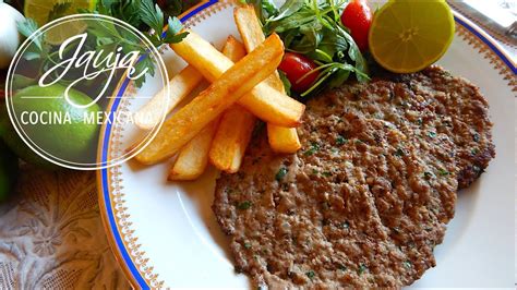 Hamburguesa de milanesa de carne molida servida con acompañamientos