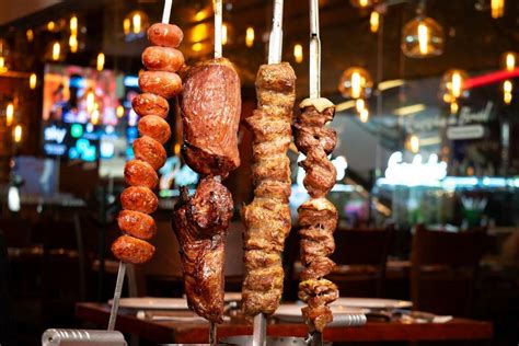 Esquema de la técnica de asado de carne a la espada brasileña o churrasco, mostrando el fuego y la rotación de las espadas