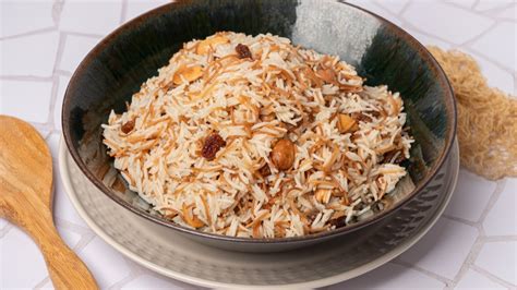 Plato de arroz turco servido con pollo, almendras y pasas de uva sobre un fondo tradicional