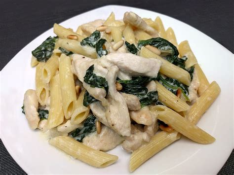 Plato terminado de penne rigate con espinacas, pollo y piñones