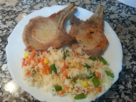 Plato terminado de chuletas de cerdo rellenas con guarnición de arroz y perejil fresco