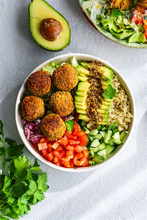 Thematic photo of a colorful rice bowl with falafel, kale, cauliflower, avocado, and pomegranate seeds.