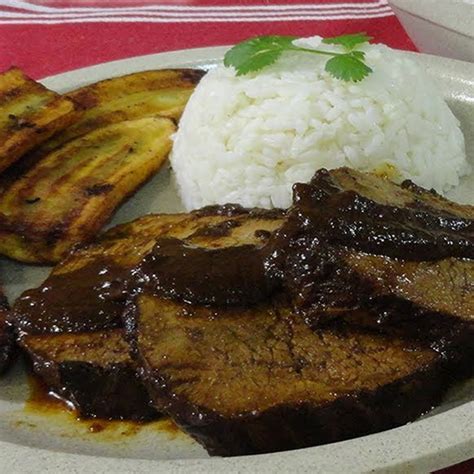 Plato de asado negro venezolano servido con arroz blanco y tajadas de plátano
