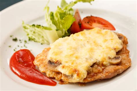 Chuleta de cerdo empanizada gratinada con queso sobre un plato