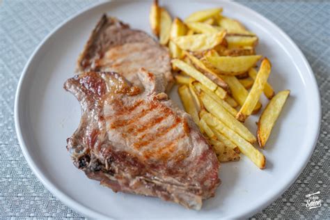 Chuletas de cerdo dorándose en una plancha caliente