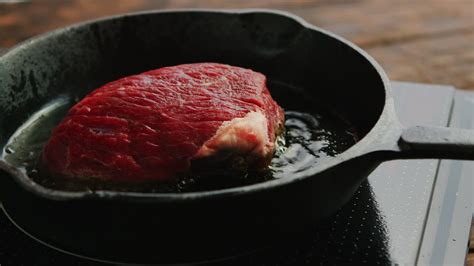 Primer plano de un sartén con arroz y carne cubierto de queso derretido.