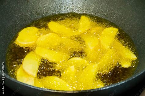 Patatas pochándose en aceite caliente en una sartén