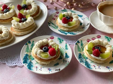 Mini panqueques decorados formando una corona navideña con frutas rojas y crema batida.