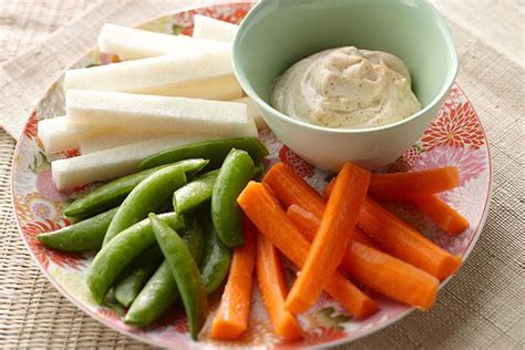 variedad de vegetales cortados en bastones y nachos servidos junto al dip de cebolla caramelizada