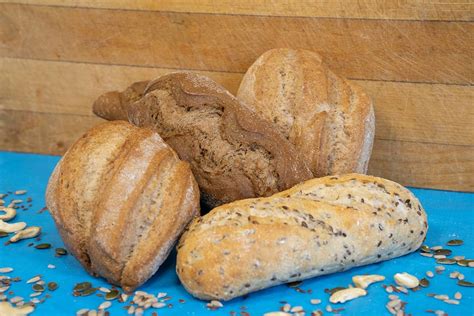 Ilustración detallada de un puesto de pan vegano artesanal con diversos tipos de pan y pasteles, decorado con elementos naturales y un letrero que indica 