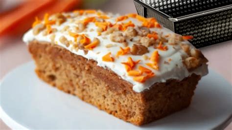 Foto principal de un trozo de budín de zanahoria y coco, con el budín entero de fondo y una taza de café