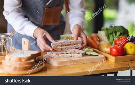 Persona preparando sándwiches con ensaladas variadas
