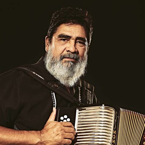 Retrato de Celso Piña tocando el acordeón, con su característica barba y sonrisa.