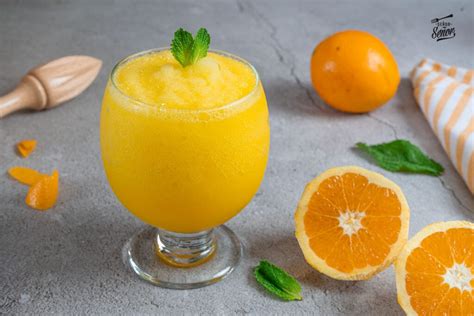 Foto de un granizado de naranja Thermomix en un vaso, con rodajas de naranja