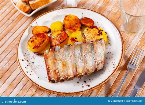 Plato de costillas de cerdo doradas servidas junto a una porción de patatas fritas caseras