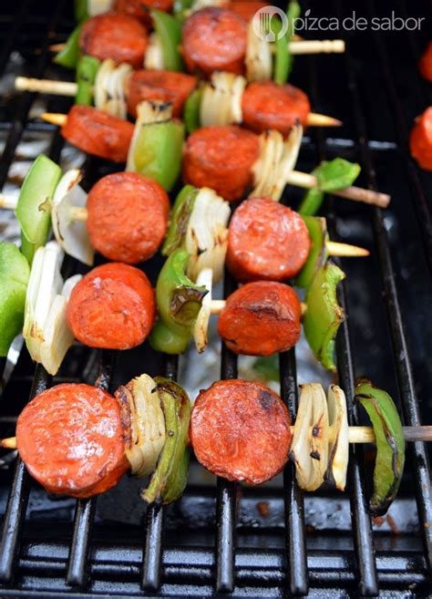Imagen de brochetas de chorizo español con pimientos y cebolla asándose en una parrilla