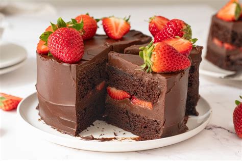 Pastel de chocolate con varias capas de bizcocho, relleno de fresas y crema, decorado con fresas frescas.