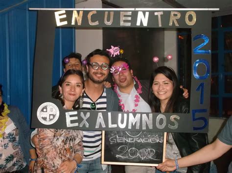 Fotografía grupal de ex alumnos durante un evento de reencuentro en un jardín, capturando la alegría y el afecto de los asistentes.
