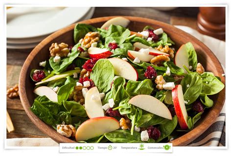 Fotografía profesional de una ensalada fresca con rodajas de kiwi, trozos de queso feta, espinacas y un aderezo brillante de vinagre balsámico.