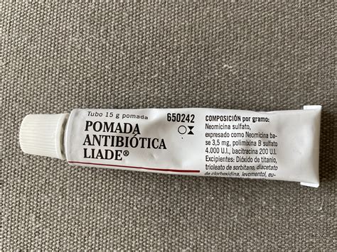 Ilustración médica mostrando la aplicación de una pomada antibiótica en una herida cutánea menor.