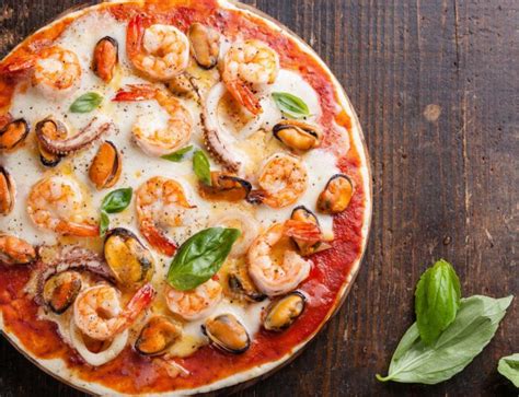 Pizza de mariscos con base de crema recién horneada, con gambas, calamares y mejillones