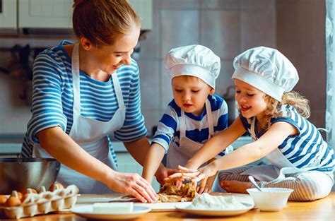 Familia cocinando junta en la cocina, niños ayudando a un adulto a preparar postres con frutas